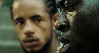 Movie still from “City of Men” (2007), directed by Paulo Morelli – A man's face with another man's face in the background; Extreme Close Up shot, Over the shoulder angle
