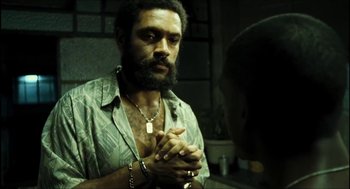 Movie still from “City of Men” (2007), directed by Paulo Morelli – A man with a beard is holding his hands together in front of a mirror; Close Up shot, Over the shoulder angle