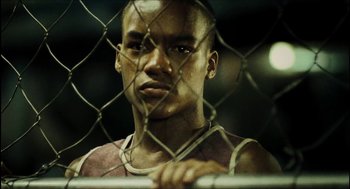 Movie still from “City of Men” (2007), directed by Paulo Morelli – A man standing in front of a chain link fence; Close Up shot, Low angle