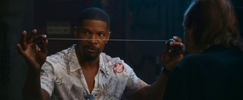 Movie still from “Day Shift” (2022), directed by J.J. Perry – A man in a hawaiian shirt holding a string; Close Up shot, Over the shoulder angle