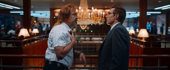 Movie still from “Day Shift” (2022), directed by J.J. Perry – Two men in business suits talking to each other; Medium shot, Over the shoulder angle