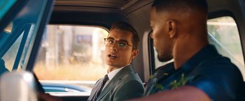 Movie still from “Day Shift” (2022), directed by J.J. Perry – A man in a suit sitting in the back of a car; Close Up shot, Over the shoulder angle