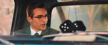 Movie still from “Day Shift” (2022), directed by J.J. Perry – A man wearing glasses and a suit in the back of a car; Close Up shot, Over the shoulder angle