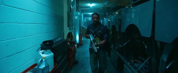 Movie still from “Day Shift” (2022), directed by J.J. Perry – A man walking down a hallway holding a pair of skis; Medium shot, Low angle