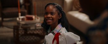Movie still from “Day Shift” (2022), directed by J.J. Perry – A young girl smiles while holding a bag of presents; Close Up shot, Over the shoulder angle