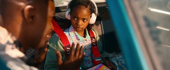 Movie still from “Day Shift” (2022), directed by J.J. Perry – A little girl wearing headphones and sitting in a car; Close Up shot, Over the shoulder angle