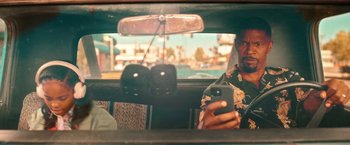 Movie still from “Day Shift” (2022), directed by J.J. Perry – A man is looking at his cell phone in the back seat of a car; Close Up shot, Over the shoulder angle