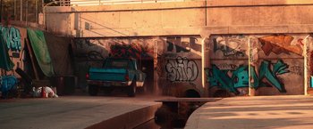 Movie still from “Day Shift” (2022), directed by J.J. Perry – A truck parked in front of a building with graffiti on it; Wide shot, High angle
