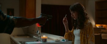 Movie still from “Day Shift” (2022), directed by J.J. Perry – A woman sitting in front of a mirror holding a gun; Medium shot, Over the shoulder angle