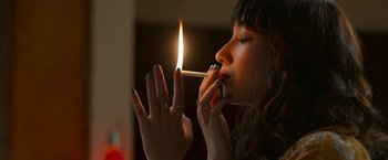 Movie still from “Day Shift” (2022), directed by J.J. Perry – A woman is lighting a cigarette with her hands; Close Up shot, High angle