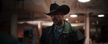 Movie still from “Day Shift” (2022), directed by J.J. Perry – A man wearing a black cowboy hat and jacket; Close Up shot, Low angle