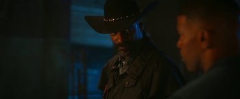 Movie still from “Day Shift” (2022), directed by J.J. Perry – A man in a black hat and a black jacket; Close Up shot, Over the shoulder angle