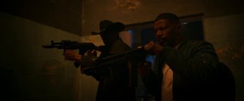 Movie still from “Day Shift” (2022), directed by J.J. Perry – Two men holding guns in a dark room; Medium shot, Low angle