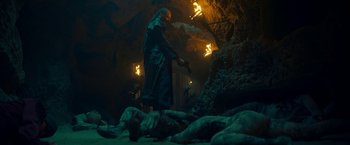 Movie still from “Day Shift” (2022), directed by J.J. Perry – A man standing over a dead body in a cave; Wide shot, Low angle