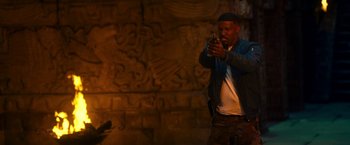 Movie still from “Day Shift” (2022), directed by J.J. Perry – A man standing in front of a brick wall holding a cell phone; Medium shot, High angle