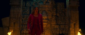 Movie still from “Day Shift” (2022), directed by J.J. Perry – A woman in a red suit standing in front of a stone wall; Wide shot, Low angle