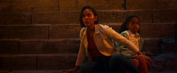 Movie still from “Day Shift” (2022), directed by J.J. Perry – A woman sitting on the ground near a set of stairs; Medium shot, High angle