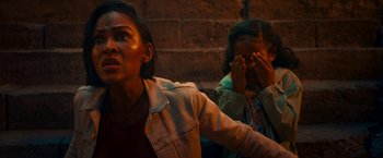 Movie still from “Day Shift” (2022), directed by J.J. Perry – Two young women sitting next to a brick wall; Close Up shot, High angle