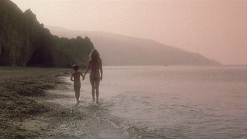 Movie still from “Clash of the Titans” (1981), directed by Desmond Davis – A woman and a child walking in the water; Wide shot, High angle