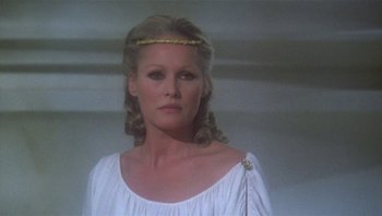 Movie still from “Clash of the Titans” (1981), directed by Desmond Davis – A woman in a white dress with a gold crown on her head; Close Up shot, Low angle