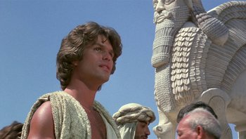 Movie still from “Clash of the Titans” (1981), directed by Desmond Davis – A man standing next to a statue of a person; Close Up shot, Low angle