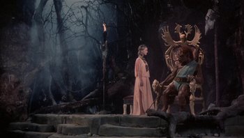 Movie still from “Clash of the Titans” (1981), directed by Desmond Davis – A man in a pink robe standing in front of statues; Wide shot, Over the shoulder angle