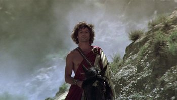 Movie still from “Clash of the Titans” (1981), directed by Desmond Davis – A man with a sword and a shield standing on top of a hill; Medium shot, Low angle