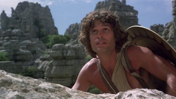 Movie still from “Clash of the Titans” (1981), directed by Desmond Davis – A man with long hair is sitting on a rock; Close Up shot, Low angle