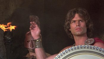 Movie still from “Clash of the Titans” (1981), directed by Desmond Davis – A man with a helmet on his head holding a sword; Close Up shot, Low angle