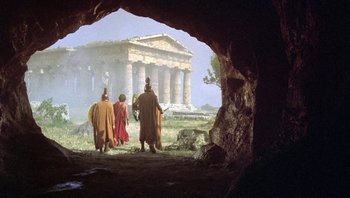 Movie still from “Clash of the Titans” (1981), directed by Desmond Davis – A group of people standing in front of an ancient building; Extreme Wide shot, Low angle