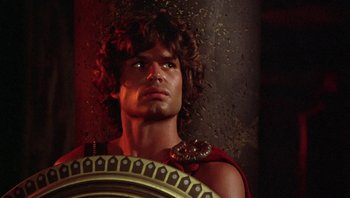 Movie still from “Clash of the Titans” (1981), directed by Desmond Davis – A man in a roman costume holding a shield in front of a brick wall; Close Up shot, Low angle