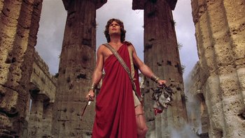 Movie still from “Clash of the Titans” (1981), directed by Desmond Davis – A man in a red robe holding a sword and looking up; Medium shot, Low angle