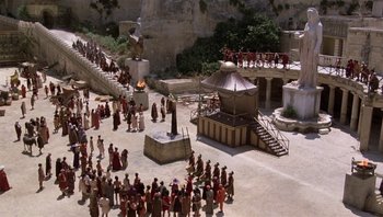 Movie still from “Clash of the Titans” (1981), directed by Desmond Davis – A crowd of people standing around a building; Extreme Wide shot, High angle