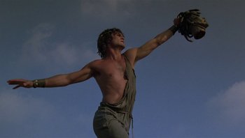 Movie still from “Clash of the Titans” (1981), directed by Desmond Davis – A shirtless man holding a baseball glove up to the sky; Medium shot, Low angle