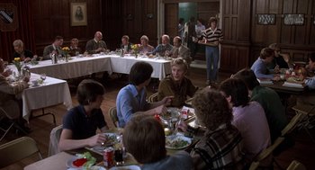 Movie still from “Class” (1983), directed by Lewis John Carlino – A group of people sitting around a table eating; Wide shot, High angle