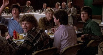 Movie still from “Class” (1983), directed by Lewis John Carlino – A group of people sitting at a table eating; Medium shot, Over the shoulder angle