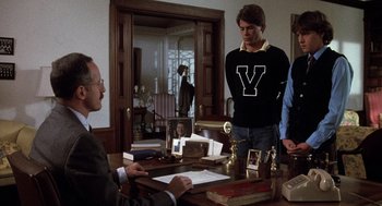 Movie still from “Class” (1983), directed by Lewis John Carlino – A group of people standing around a table; Medium shot, Over the shoulder angle