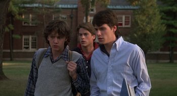 Movie still from “Class” (1983), directed by Lewis John Carlino – A group of young men standing next to each other on a sidewalk; Medium shot, Over the shoulder angle