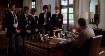 Movie still from “Class” (1983), directed by Lewis John Carlino – A group of young men standing in front of a desk; Wide shot, Over the shoulder angle