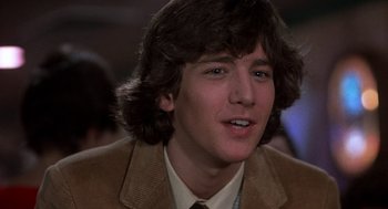 Movie still from “Class” (1983), directed by Lewis John Carlino – A man with long brown hair wearing a brown jacket; Close Up shot, Over the shoulder angle