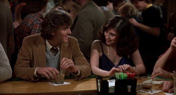 Movie still from “Class” (1983), directed by Lewis John Carlino – A man and a woman sitting at a table at a party; Medium shot, Over the shoulder angle