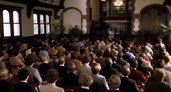 Movie still from “Class” (1983), directed by Lewis John Carlino – A group of people sitting in front of a microphone; Wide shot, High angle