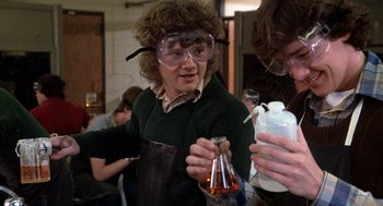 Movie still from “Class” (1983), directed by Lewis John Carlino – A man wearing goggles and holding a flask; Medium shot, Low angle