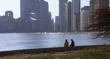 Movie still from “Class” (1983), directed by Lewis John Carlino – Two people sitting on a wall near a body of water; Extreme Wide shot, High angle