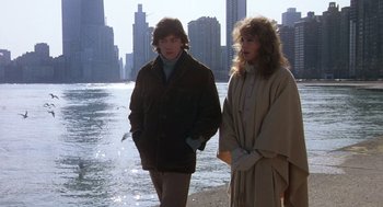 Movie still from “Class” (1983), directed by Lewis John Carlino – A man and a woman standing next to a body of water; Wide shot, High angle