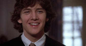 Movie still from “Class” (1983), directed by Lewis John Carlino – A person wearing a suit and tie smiling; Close Up shot, Low angle