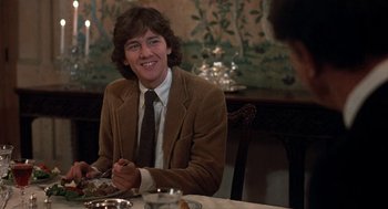 Movie still from “Class” (1983), directed by Lewis John Carlino – A man sitting at a dinner table smiling for the camera; Medium shot, Over the shoulder angle