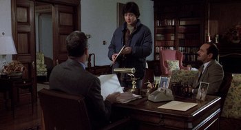 Movie still from “Class” (1983), directed by Lewis John Carlino – A man and a woman are sitting at a desk; Medium shot, High angle