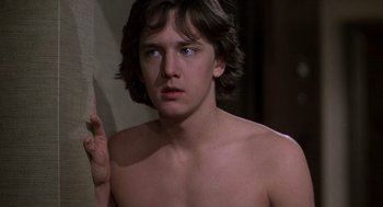Movie still from “Class” (1983), directed by Lewis John Carlino – A young man with long brown hair and blue eyes is posing for the camera; Close Up shot, Low angle