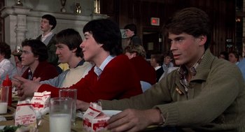 Movie still from “Class” (1983), directed by Lewis John Carlino – A group of young men sitting at a table; Medium shot, Over the shoulder angle
